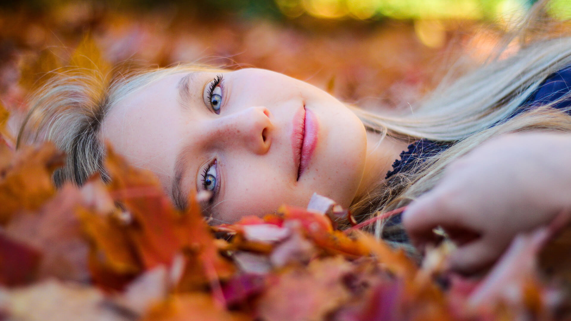 A woman lies on fall leaves