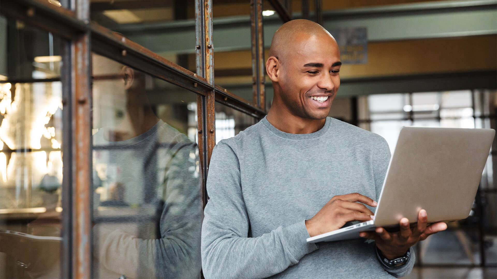 A man smiles as he looks at his laptop