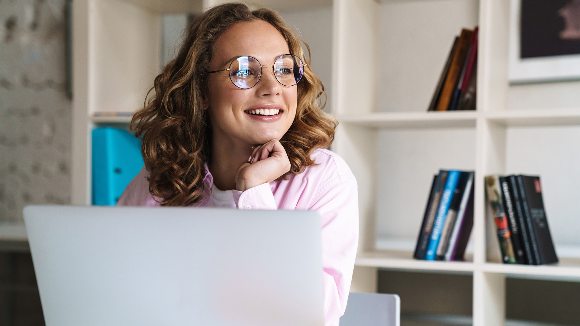 A woman sitting with her computer looking the other way and smiling.