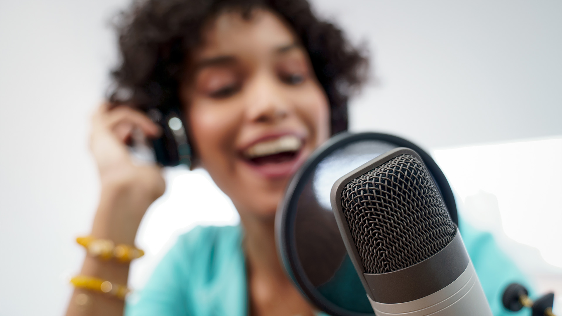 A female speaking into a microphone for a podcast.