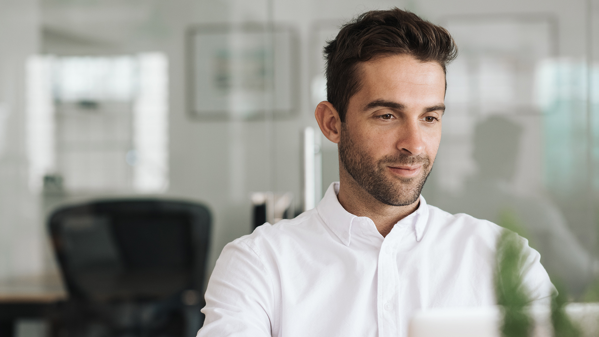 A man in a button up shirt sitting at his desk.