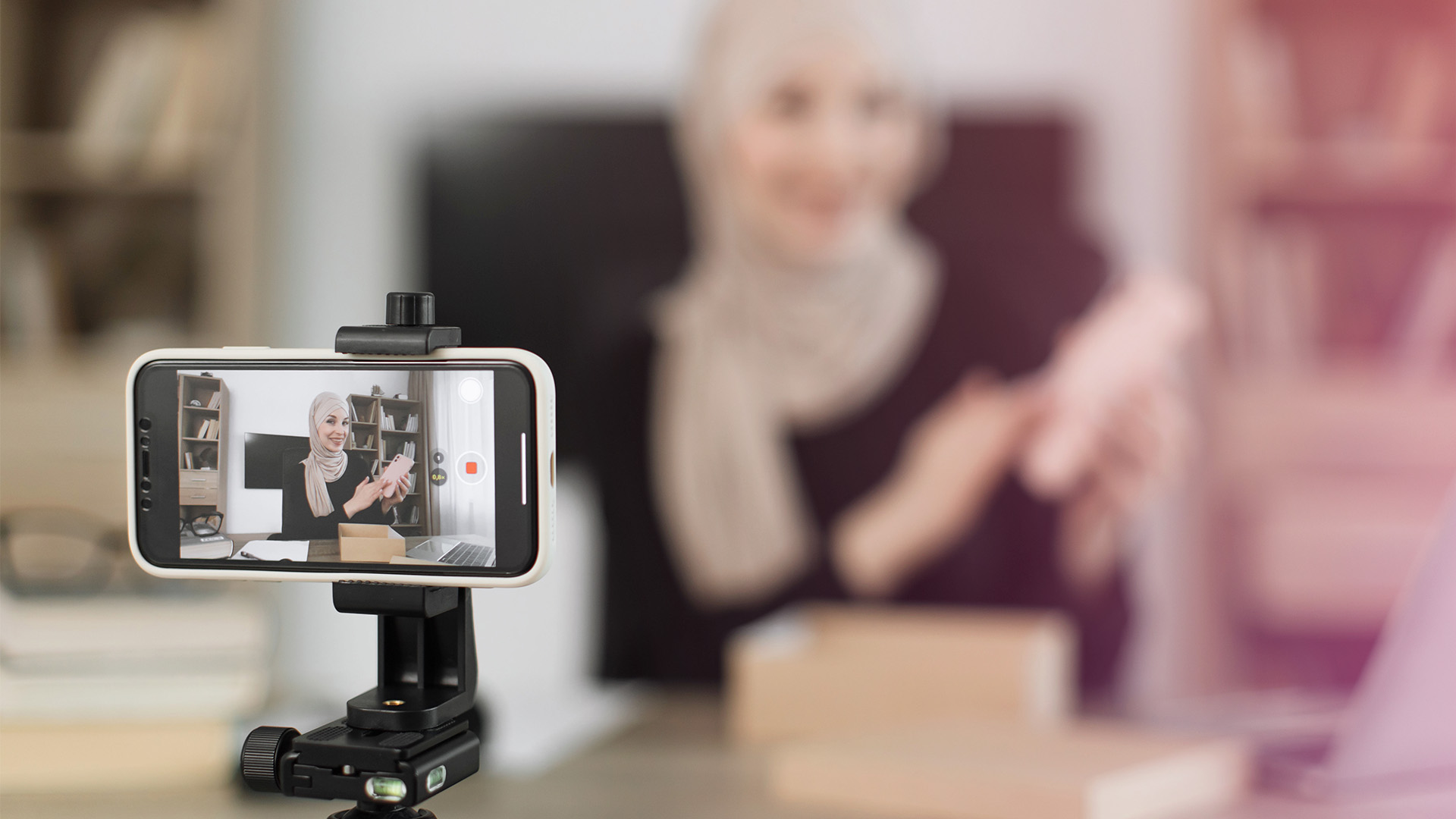 A woman films a video on her phone, which is mounted horizontally on a small tripod